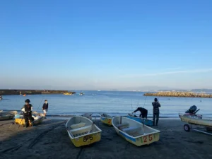 [森戸海岸で出船準備をする手漕ぎボートと釣り人]